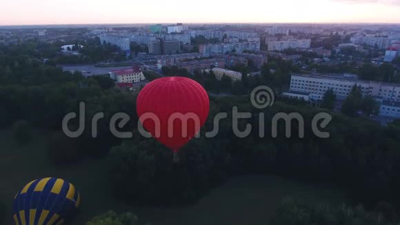 黎明时分红热气球飘过城市绿地节日早飞视频的预览图