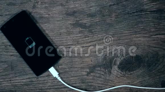 在grungewood背景上使用白色电缆为智能手机充电视频的预览图