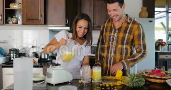一对夫妇在酒杯中倒入鲜榨果汁在厨房中品尝男人和女人在一起谈论快乐的微笑视频的预览图