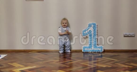 一个快乐的一岁男孩在地板上庆祝生日和跳舞视频的预览图