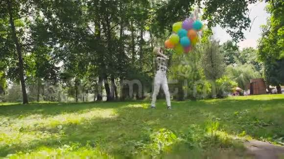 快乐的年轻女孩在公园里用五颜六色的气球在镜头前散步和摆姿势视频的预览图