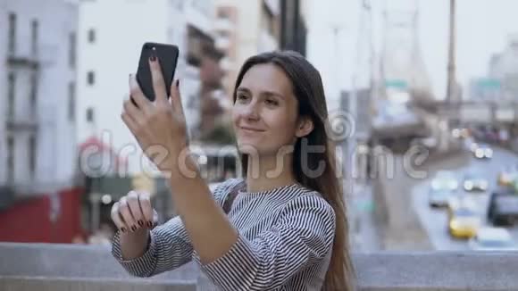 年轻快乐的美女在智能手机上自拍背景上有汽车和出租车的交通道路视频的预览图