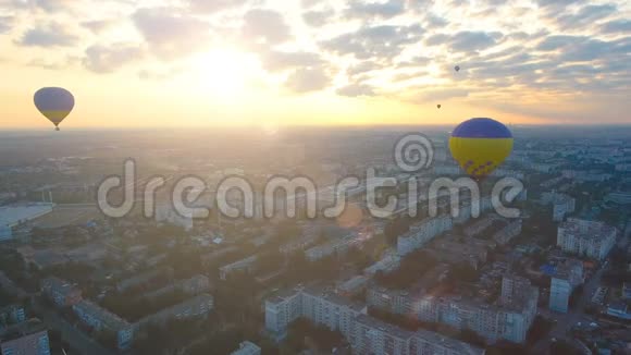 在城市上空漂浮着几个热气球迎着初升的太阳飞行视频的预览图
