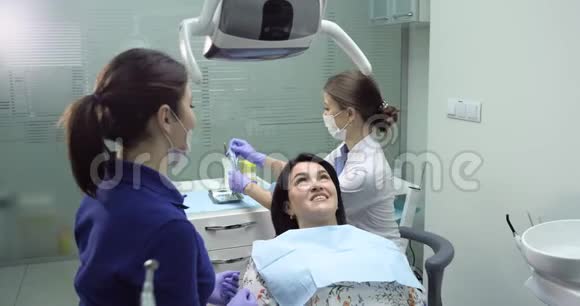 牙医为一名年轻妇女做检查和牙科清洁牙科护士在旁边视频的预览图
