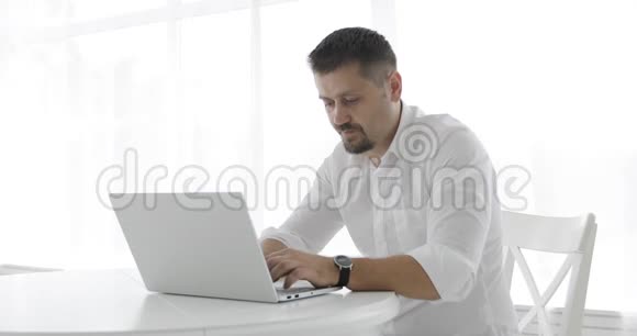 穿着白色衬衫的时髦商人紧张地在笔记本电脑上打字并关闭它视频的预览图