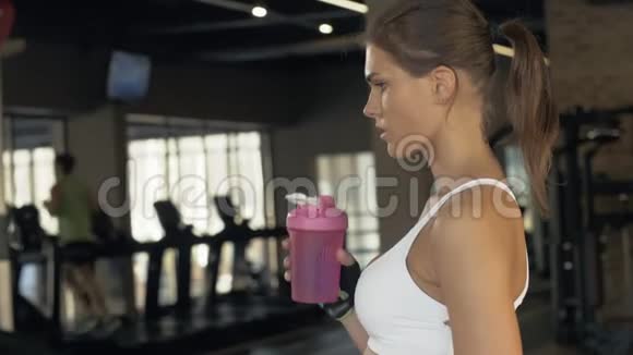 在俱乐部进行耐力训练后口渴的女人喝一瓶冷水视频的预览图