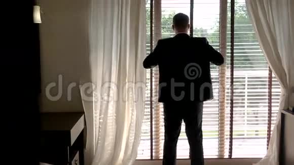 穿西装的人靠近窗户视频的预览图