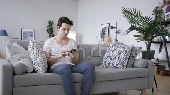愤怒的尖叫男人打电话坐在沙发上视频的预览图