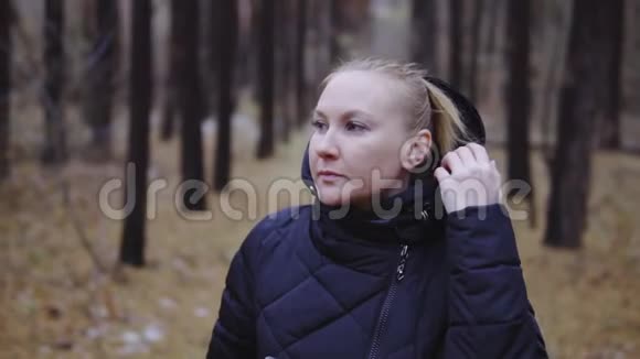 电影拍摄慢动作那个金发女孩穿着夹克沿着秋天的森林散步第一场雪视频的预览图