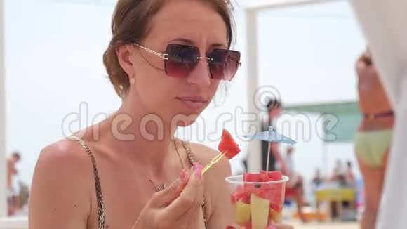 快乐的女孩在海滩上吃西瓜片暑假户外野餐视频的预览图