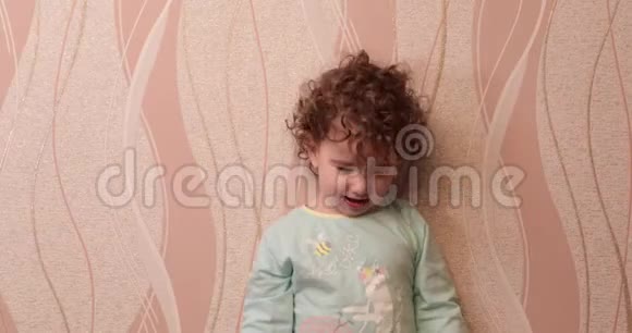 小卷发女孩微笑着在家里墙上扔毛绒玩具视频的预览图