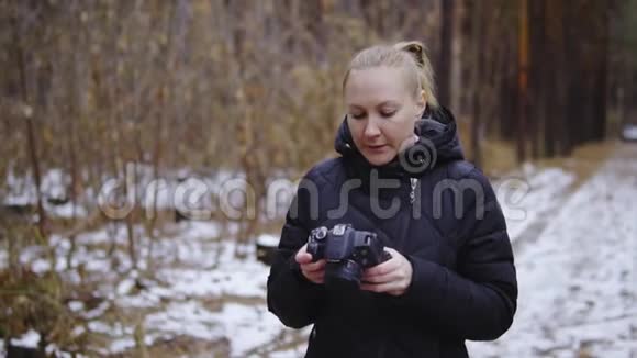 电影拍摄慢动作女孩摄影师穿过秋天的森林拍摄大自然的照片持有视频的预览图