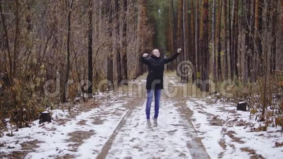 女孩在森林里缓慢地跳跃享受一年中的第一场雪秋季森林视频的预览图