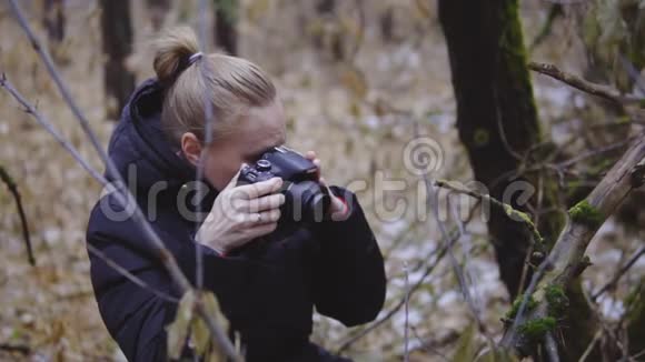 摄影师女孩走在秋木上拍摄大自然的照片第一场雪电影镜头慢慢慢慢视频的预览图