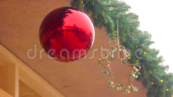 行人在明亮的圣诞球中的倒影挂在房子的屋顶下视频的预览图