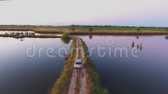 空中摄影汽车沿着湖之间的一条狭窄的道路行驶鱼塘夏日的早晨伊万诺夫斯卡亚视频的预览图
