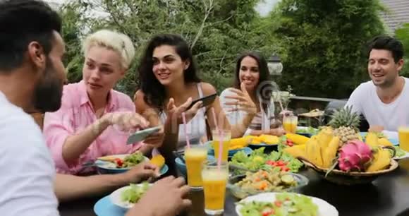 利用智能手机朋友在热带露台上交流健康素食饮食视频的预览图