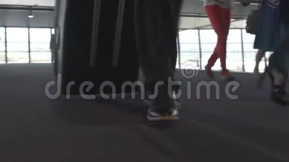 女性和男性双腿在铺有地毯的机场地板上行走带手提箱出发视频的预览图