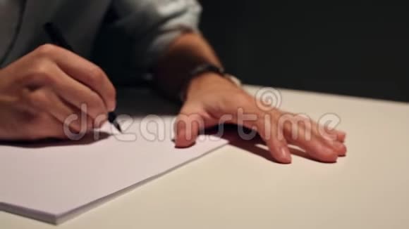 人在白纸上画画或写作商业的宏观镜头穿着衬衫写在桌子后面的纸上视频的预览图