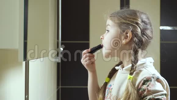 迷人的小女孩在镜子前用口红涂嘴唇视频的预览图