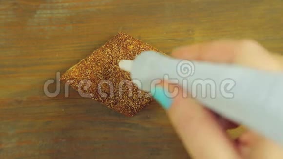 一只手握着一管烹饪颜料在一块带有红色颜料的巧克力饼干上画着心视频的预览图