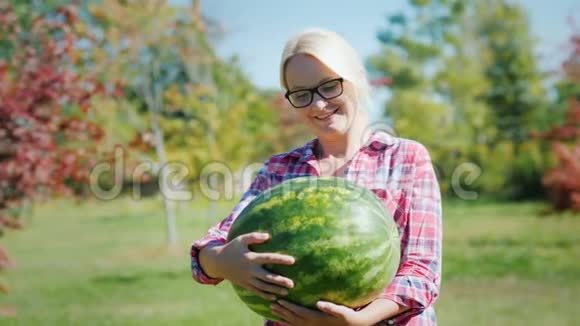 一个女农民抱着一个大西瓜的肖像看着镜头微笑着视频的预览图