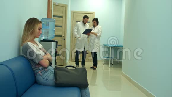 两位医生讨论诊断时忧心忡忡的女病人在医院大厅等候视频的预览图