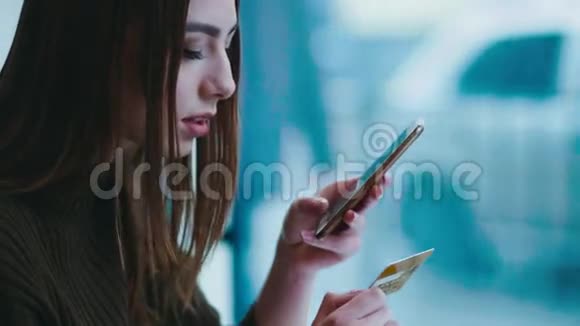 漂亮的黑发女人用她的手机和信用卡进行网上购物现代技术当代人视频的预览图