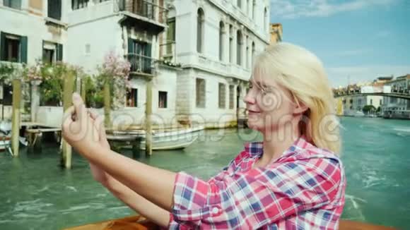 一位年轻女子在威尼斯的背景下照了一张自己的照片她坐在大运河上的出租车在大运河上航行视频的预览图