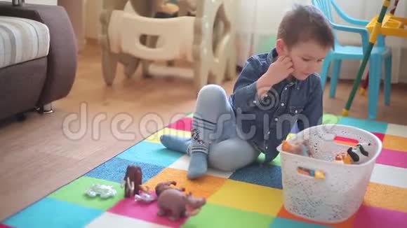 小男孩坐在地板上玩各种动物视频的预览图