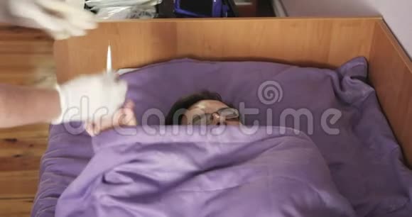 一个戴眼镜的生病的年轻人躺在床上测量温度视频的预览图