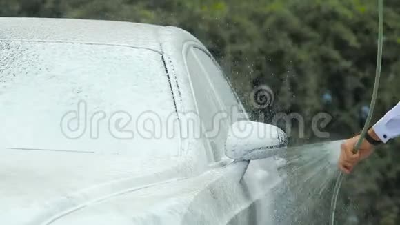 男性喷洒泡沫肥皂车司机照顾车辆洗车视频的预览图