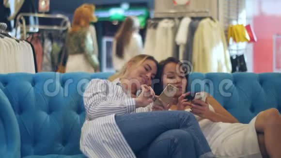 带着智能手机和购物袋的快乐年轻女性在商场聊天视频的预览图
