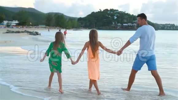 爸爸和孩子们享受海滩暑假热带假期一家人在海边散步流动人口视频的预览图