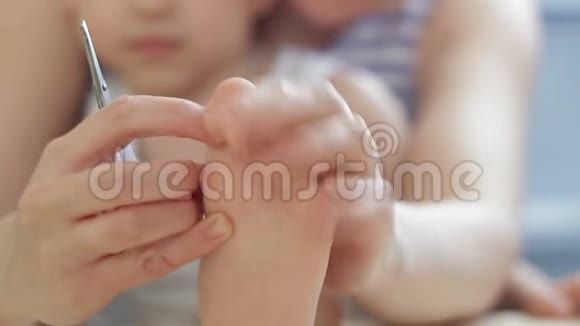 妈妈从孩子身上剪下了婴儿腿上的指甲视频的预览图