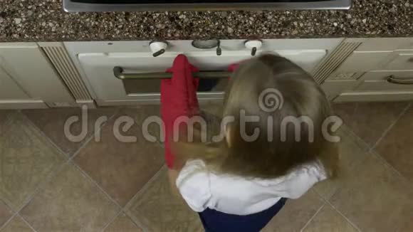 女孩从烤箱里拿托盘和饼干姜饼望着顶部微笑她手上戴着红色手套视频的预览图