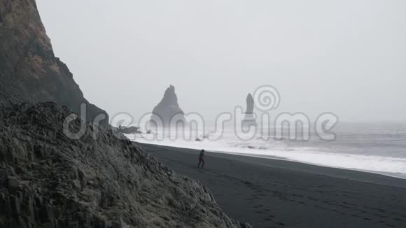 一个女孩正沿着冰岛荒芜的海滩散步视频的预览图