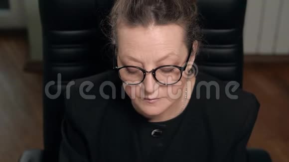 戴眼镜的黑发成熟女人坐在椅子上工作电脑视频的预览图