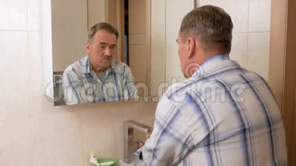 老人在洗澡时把头发弄直了他照镜子仔细检查头发自我的概念视频的预览图