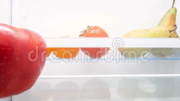 4K画面饥饿的年轻女子在冰箱里看吃红苹果视频的预览图