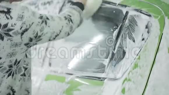 一个女人用海绵和泡沫清洗洗车处所里的绿色机器视频的预览图