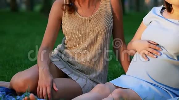 孕妇和她的朋友坐在草地上视频的预览图