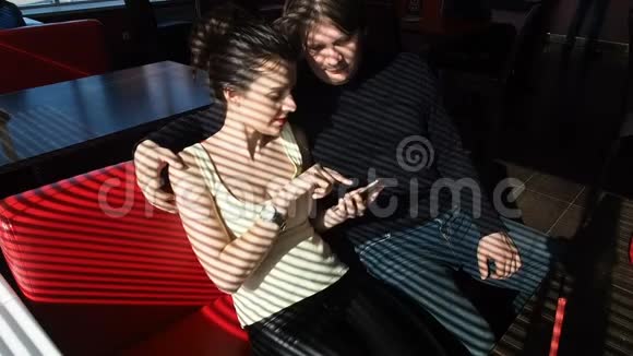 女人和男人坐在咖啡馆的桌子旁女孩在手机上显示了一些东西微笑着他拥抱了她视频的预览图