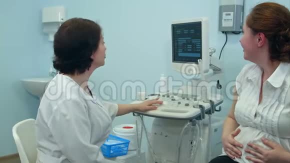 快乐的孕妇与微笑的女医生交谈视频的预览图