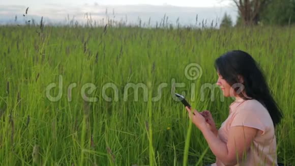 一个女人坐在绿草中在公园里的一块石碑上工作摄像机移动到杜莉视频的预览图