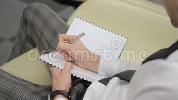 年轻人在笔记本上写字坐在现代办公室里视频的预览图