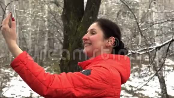 穿橙色夹克的女人在雪木里自拍这位美丽的女人被拍在视频的预览图