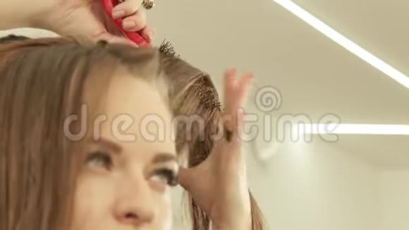 女理发师在美容院理发时用梳子梳理头发做女性发型师视频的预览图