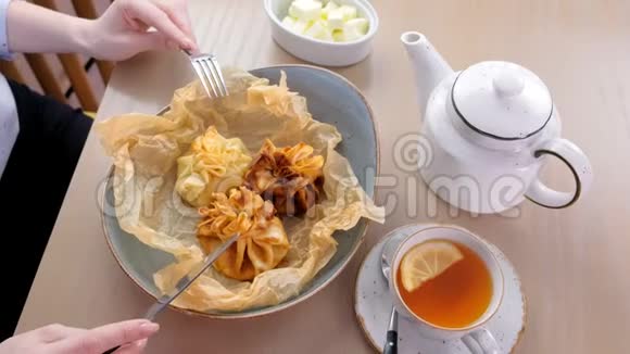 女人正在吃朱莉安烘焙的面团放在面包纸上上面有茶和黄油双手特写视频的预览图