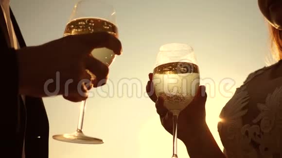 恋爱中的情侣拿着酒杯在夕阳的背景下喝着起泡葡萄酒特写镜头爱的一对夫妻的团队合作视频的预览图